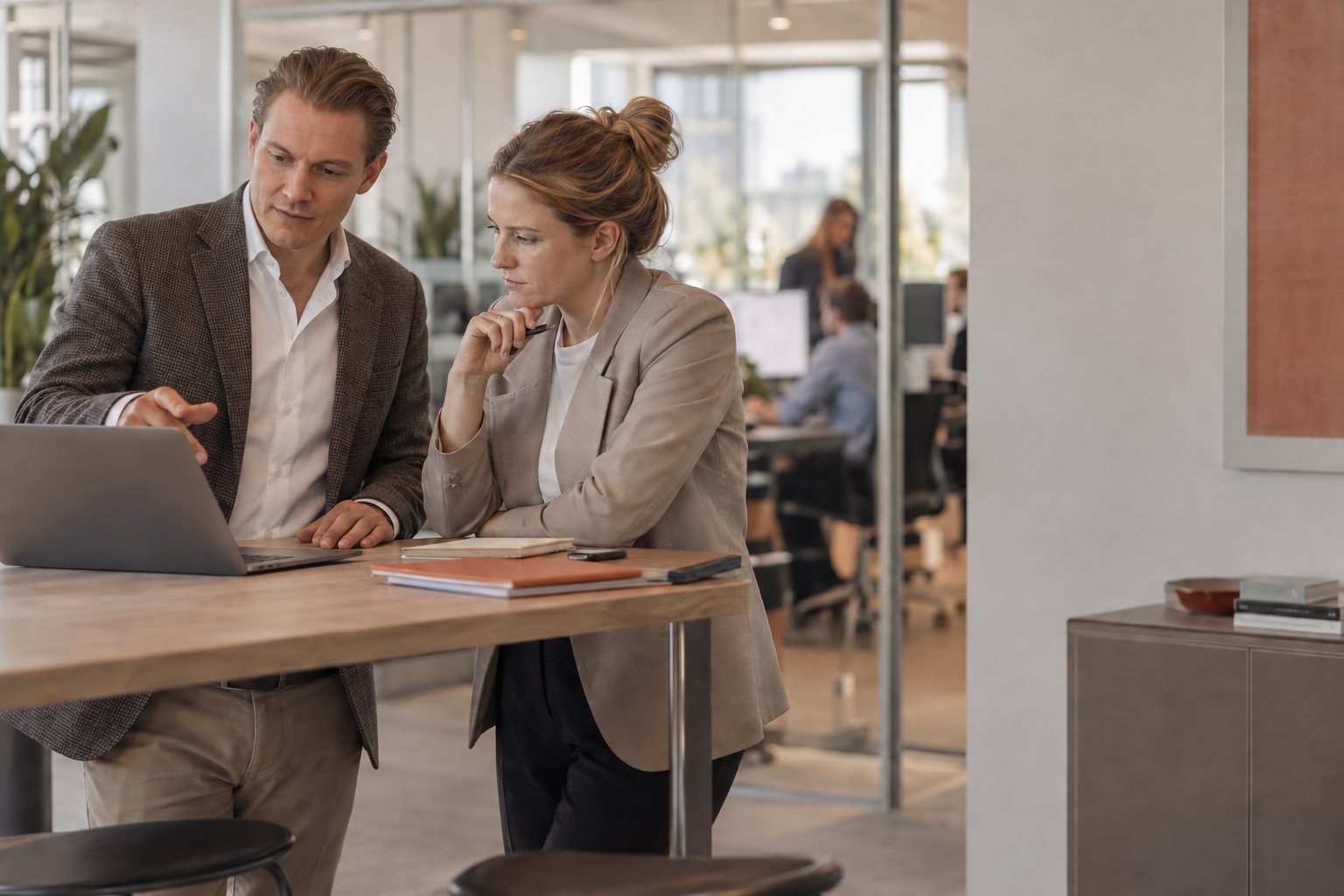 Consultant and client discussing figures on a laptop at a standing table